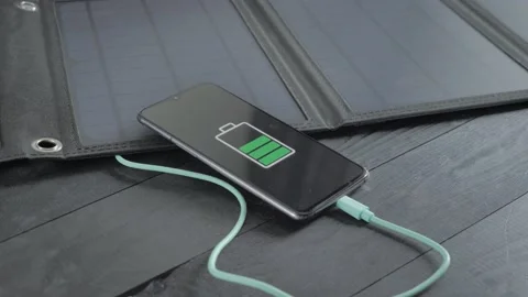 Charging a smartphone with a portable solar panel Stock Footage 201684877