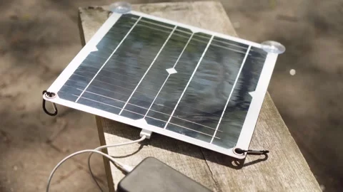 Charging a smartphone with a portable solar panel. camping. Stock Footage 241405195