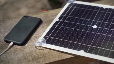 Charging a smartphone with a portable solar panel. camping. Stock Footage 241493260