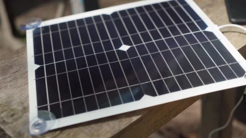 Charging a smartphone with a portable solar panel. camping. Stock Footage 241493345