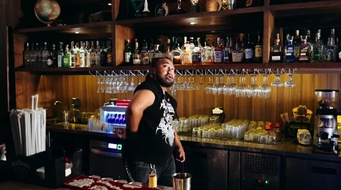 Charismatic bartender with piercings and dreadlocks practices juggling bottle Stock Footage 65398905