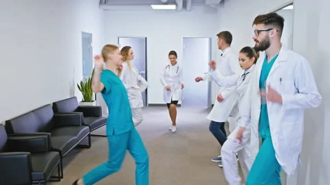 Charismatic doctors and nurses dancing excited in the hospital corridor they Stock Footage 130517974