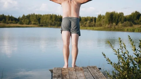 Charismatic guy runs up and jumps from the pier into the water. Cheerful man Stock Footage 115406044