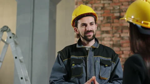 Charismatic handsome constructor worker man have a discussion with a woman at Stock Footage 202066705
