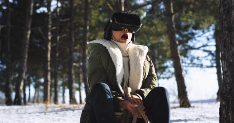 Charismatic lady very impressed using a virtual reality glasses to play a ride Stock Footage 111970175
