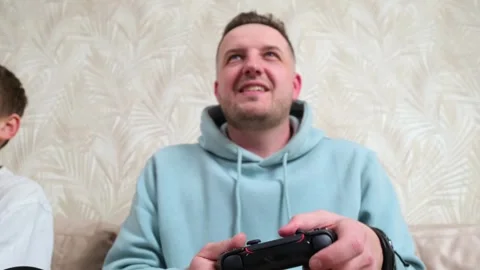 Charismatic man playing video console at home on vacation Stock Footage 268267624