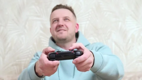 Charismatic man playing video console at home on vacation 動画素材 268301441