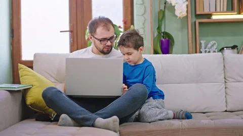 Charismatic small boy with his dad have a fun time together using a laptop to Stock Footage 139050524