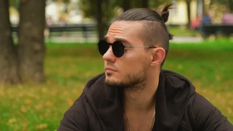 A charismatic young man in dark round glasses looks around. Close-up. Stock Footage 139909385
