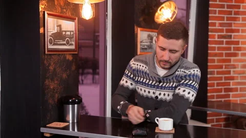 Charismatic young man drinks coffee and uses a smartphone in a restaurant Stock-Footage 87050063