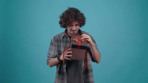 The charismatic young man, eagerly opens the gift, with high hopes, after seeing Stock Footage 153084877