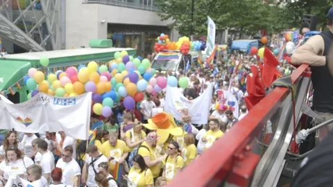 CHARITIES IN THE PRIDE MARCH WITH BALLOONS AND CROWDS AT GAY PRIDE Stock Footage 130743336