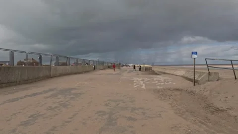 Charity runners running along a seafront next to a sandy beach with grey st.. Stock Footage 240285774