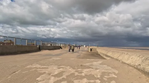 Charity runners running along a seafront next to a sandy beach with grey st.. Stock Footage 240285992