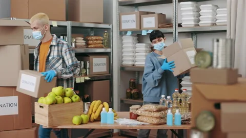 Charity workers in face masks preparing boxes with grocery Stock Footage 173603573