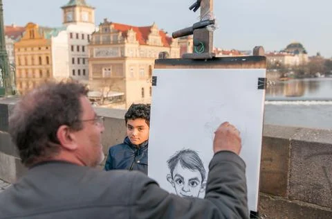 The Charles Bridge is crowded of people, while tourists enjoy walking interac Stock Photos