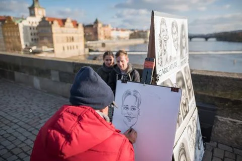 The Charles Bridge is crowded of people, while tourists enjoy walking interac Stock Photos