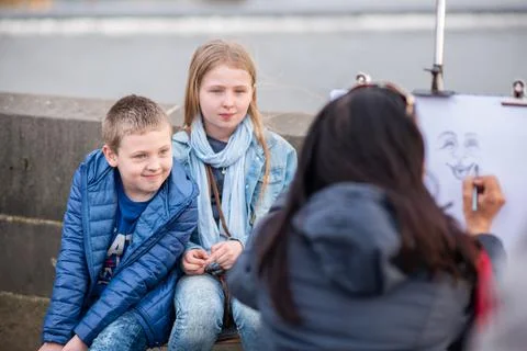The Charles Bridge is crowded of people, while tourists enjoy walking interac Stock Photos