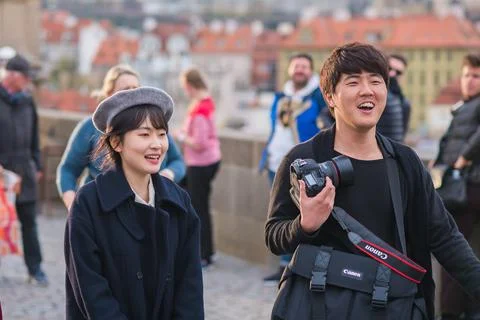 The Charles Bridge is crowded of people, while tourists enjoy walking interac Stock Photos