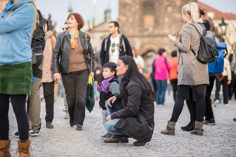 The Charles Bridge is crowded of people, while tourists enjoy walking interac Stock Photos