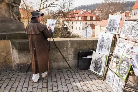 The Charles Bridge is crowded of people, while tourists enjoy walking interac Stock Photos