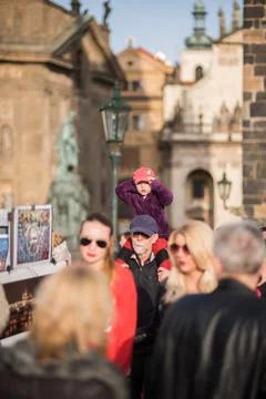 The Charles Bridge is crowded of people, while tourists enjoy walking interac Stock Photos