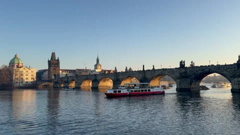 Charles Bridge at Golden hour while boats pass by on the Vltava River Stock Footage 340079609