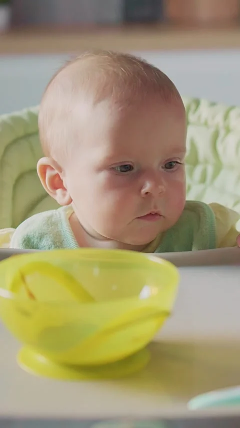 A Charming Baby is Curiously Exploring an EyeCatching Yellow Bowl Filled with Stock Footage 314209474