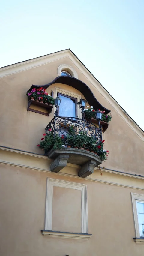 A charming balcony on a light beige facade with a wrought iron railing, adorned  Stock Footage 293466140