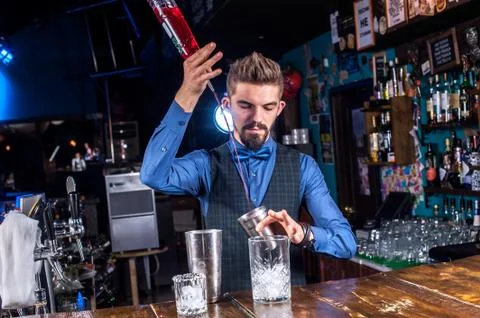 Charming barman demonstrates the process of making a cocktail at the nightclub Foto stock