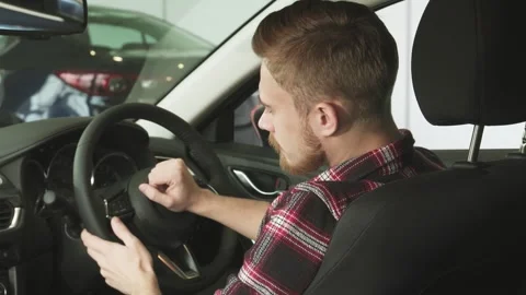 Charming bearded man joyfully smiling over his shoulder in a sleek new car Stock Footage 311988648