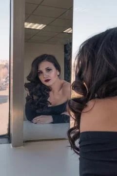 Charming beautiful girl admiring herself in the mirror Stock Photos