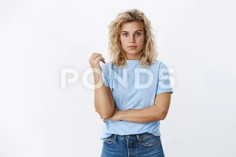 Charming blond girl with blue eyes and curly hairstyle standing in casual Stock Photos