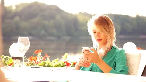 Charming blond girl drinks vine and chat with iPhone in restaurant Stock Footage 78684792