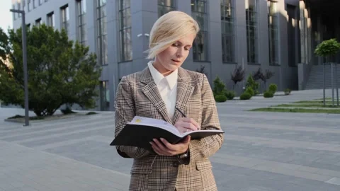 Charming blonde holds a notebook in her hands and makes a note. 스톡 동영상 136727392