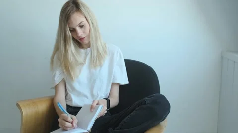 Charming blonde woman writes in a notebook Stock Footage