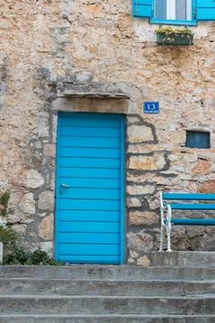 Charming Blue Door on Rustic Stone Wall With Matching Bench Stock Photos