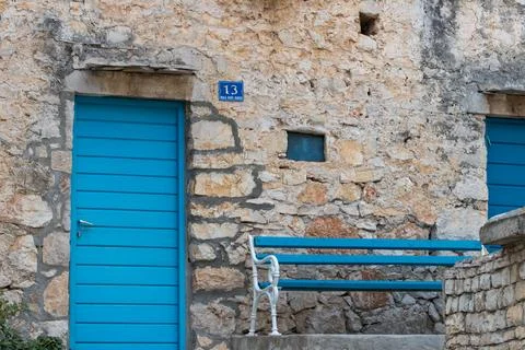 Charming Blue Door on Rustic Stone Wall With Matching Bench Stock Photos