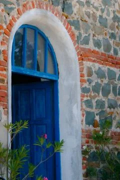 Charming blue door on stone wall surrounded by vibrant greenery Stock Photos