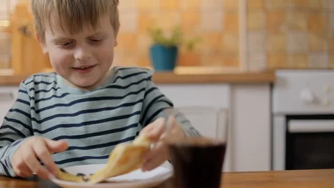 Charming boy sitting on the kitchen and eating pizza Stock Footage 103221203