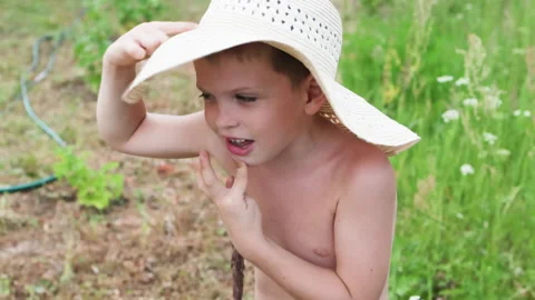 Charming boy in straw hat joyfully explores garden. Video stock 287533317