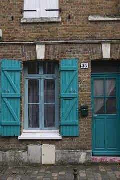 A Charming Brick Facade adorned with Turquoise Shutters in Vibrant Urban Se.. Stock Photos