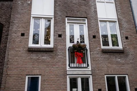 A charming brick facade features white framed windows and a small balcony 写真素材