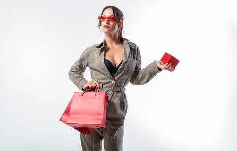 Charming brunette in glasses posing in the studio with red bags and a box f.. Stock Photos