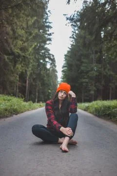 Charming brunette sitting on a path surrounded by wild nature, enjoying the f Stock Photos