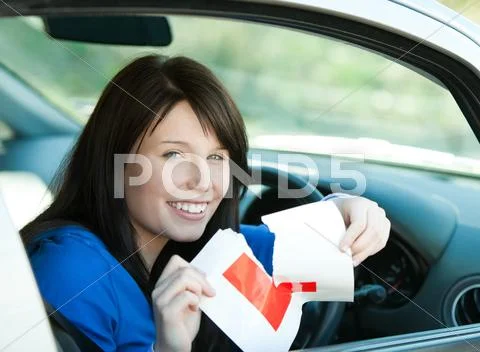 Charming brunette teen girl sitting in her car tearing a L-sign Stock Photos