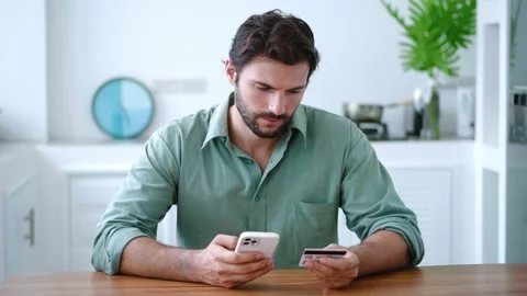 Charming Caucasian bearded dark-haired guy holding a credit card and modern Stock Footage 212419676