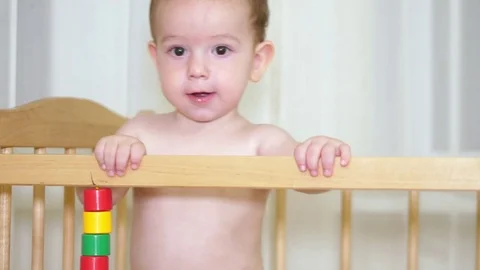 The charming child in the crib laughs and moves around the crib and at the same Stock Footage 79470256