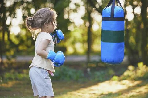 Charming child doing boxing in the backyard on the Sunset Stock Photos