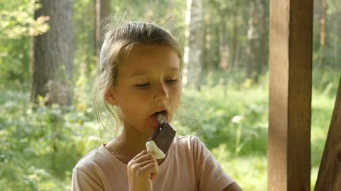 Charming child eats ice cream outdoors. Little girl licking ice-cream Stock Footage 94027931